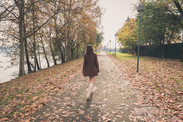 Beautiful young woman walking in a city park — Stock Photo, Image