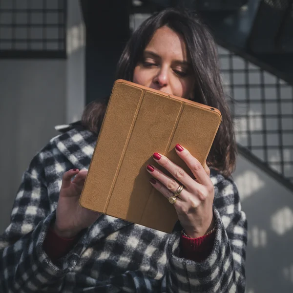 Beautiful young brunette using her tablet in the city streets — Stock Photo, Image