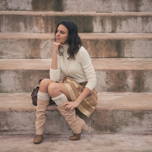 Beautiful young woman sitting on concrete steps — Stock Photo, Image