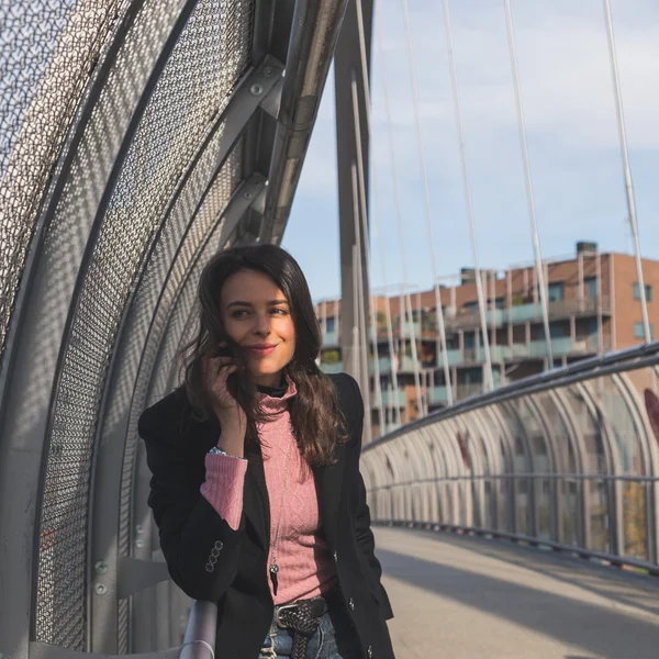 Beautiful young brunette posing on a bridge — Stock Photo, Image