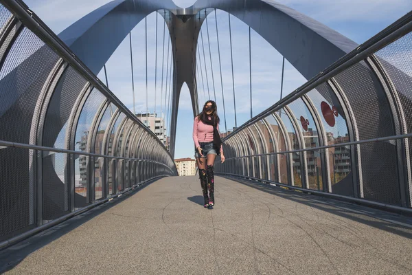 Beautiful young brunette jumping on a bridge — Stock Photo, Image