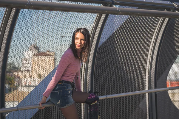 Mooie jonge brunette die zich voordeed op een brug — Stockfoto