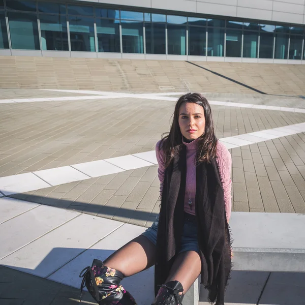 Beautiful young brunette sitting on a bench — Stock Photo, Image