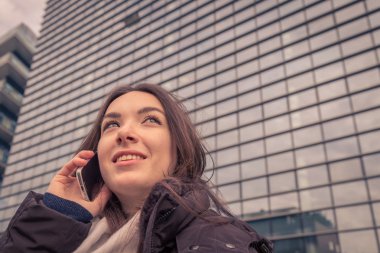 Şehir sokaklarında telefonda konuşurken genç güzel kız