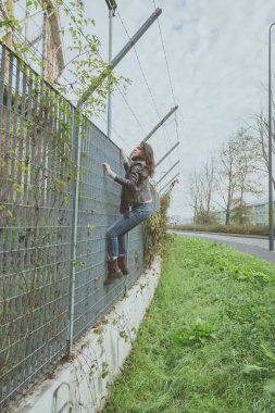 Güzel genç esmer bir çitin üzerinden tırmanma