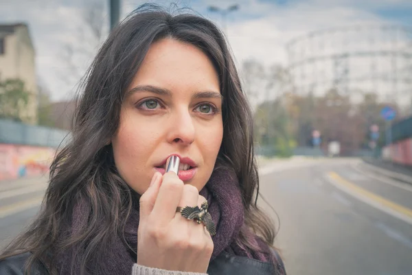 Hermosa joven morena poniendo lápiz labial en las calles de la ciudad —  Fotos de Stock