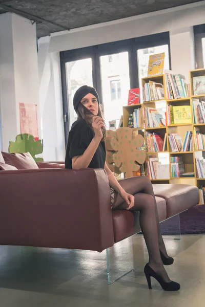 Vacker ung brunett poserar i en bokhandel — Stockfoto