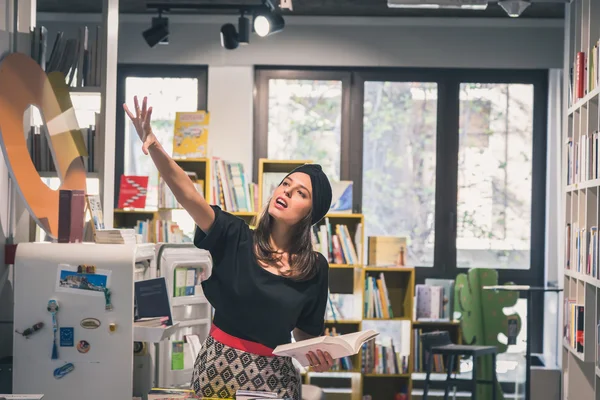 Schöne junge Brünette posiert in einer Buchhandlung — Stockfoto