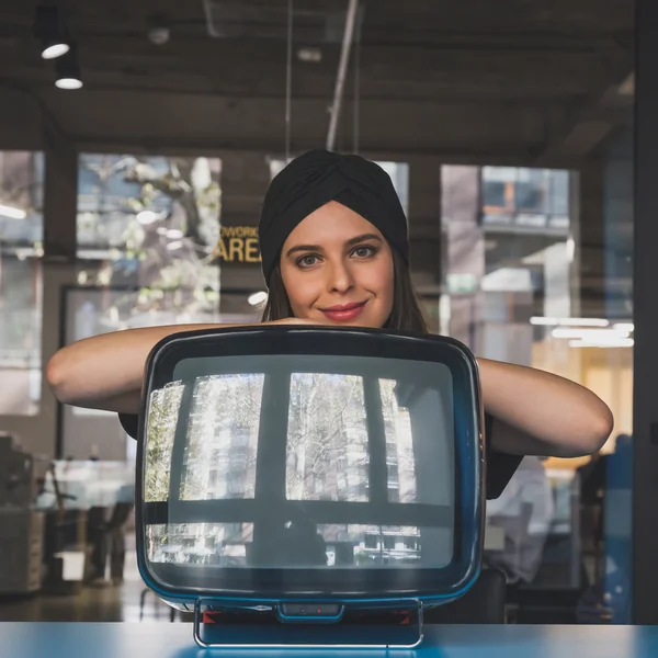 Beautiful young brunette posing beside a vintage tv — Stock Photo, Image