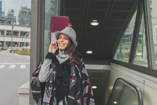 Bella giovane bruna che parla al telefono per le strade della città — Foto Stock