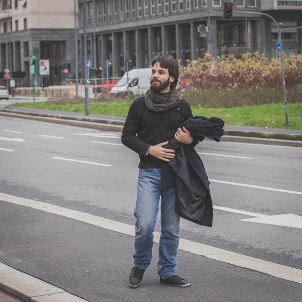 Mladý pohledný vousatý muž pózuje v ulicích města — Stock fotografie