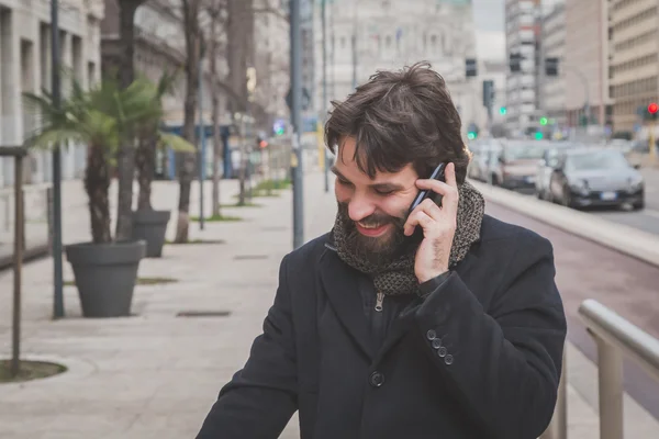 Genç yakışıklı sakallı adam telefonda konuşurken — Stok fotoğraf