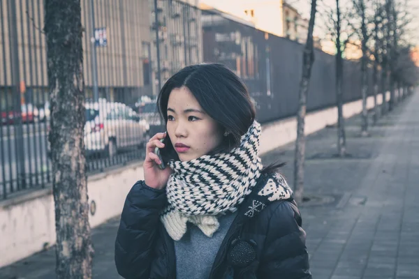 年轻漂亮的中国女孩谈电话在城市的街道 — 图库照片
