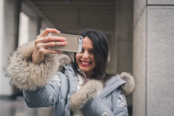 Vacker ung brunett med en selfie på stadens gator — Stockfoto