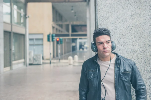 Fiatal jóképű férfi fejhallgató pózol a város utcáin — Stock Fotó