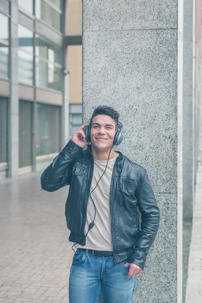 Young handsome man with headphones posing in the city streets — Stock Photo, Image