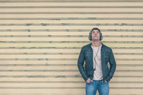 Young handsome man with headphones posing in the city streets — Stock Photo, Image