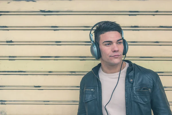 Jovem bonito homem com fones de ouvido posando nas ruas da cidade — Fotografia de Stock