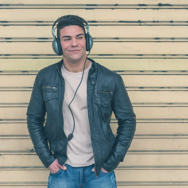 Young handsome man with headphones posing in the city streets — Stock Photo, Image