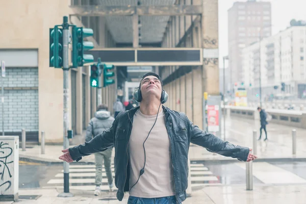 Joven hombre guapo con auriculares posando en las calles de la ciudad — Foto de Stock