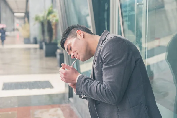 Jovem homem bonito fumando um cigarro — Fotografia de Stock