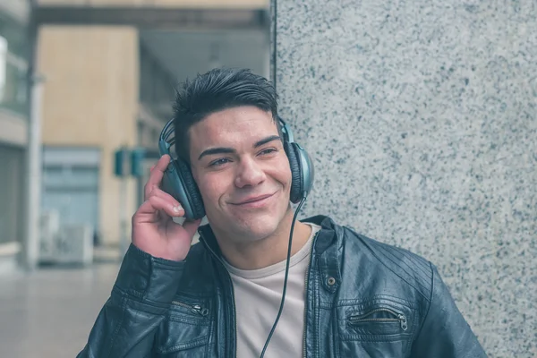 Młody przystojny mężczyzna z słuchawki pozowanie na ulicach miasta — Zdjęcie stockowe