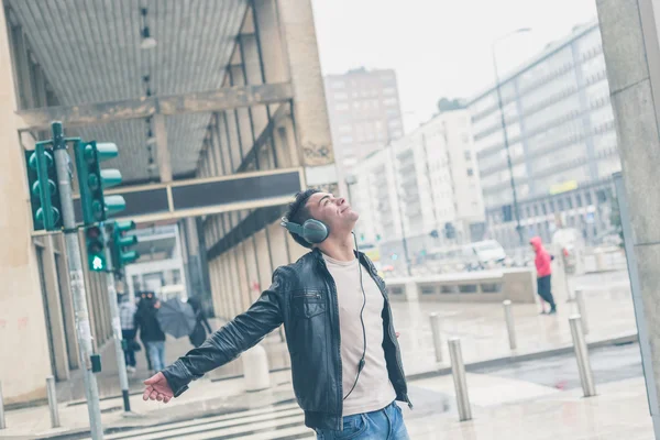 Jovem bonito homem com fones de ouvido posando nas ruas da cidade — Fotografia de Stock