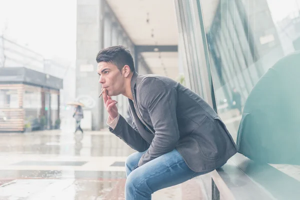 Jovem homem bonito fumando um cigarro — Fotografia de Stock