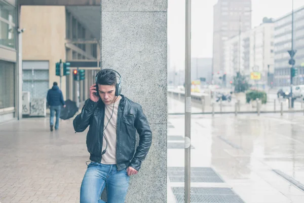 Молодий красивий чоловік з навушниками позує на міських вулицях — стокове фото