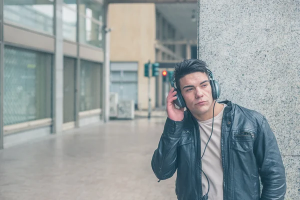 Młody przystojny mężczyzna z słuchawki pozowanie na ulicach miasta — Zdjęcie stockowe