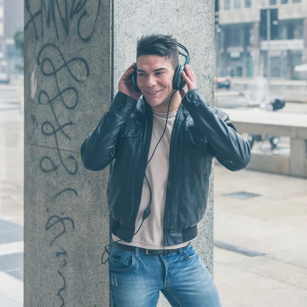 Jovem bonito homem com fones de ouvido posando nas ruas da cidade — Fotografia de Stock