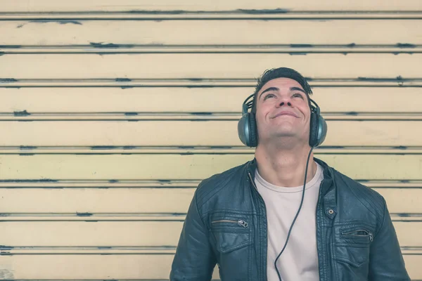 Young handsome man with headphones posing in the city streets — Stock Photo, Image