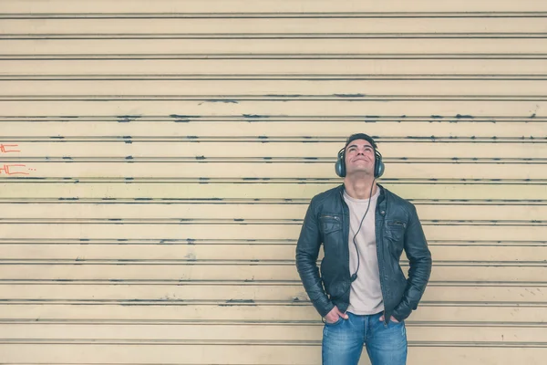 Young handsome man with headphones posing in the city streets — Stock Photo, Image