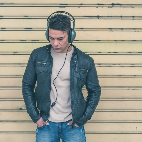 Jovem bonito homem com fones de ouvido posando nas ruas da cidade — Fotografia de Stock