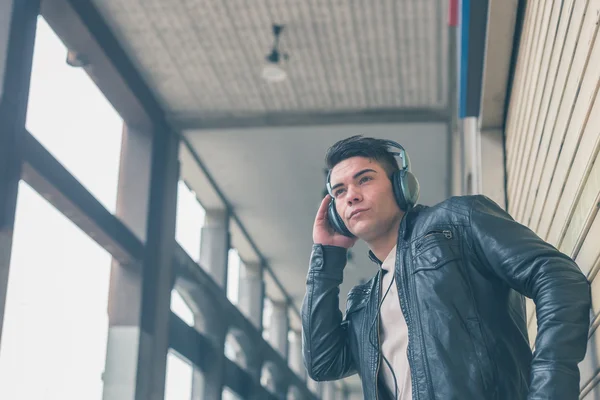 Young handsome man with headphones posing in the city streets — Stock Photo, Image