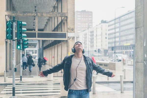 Joven hombre guapo con auriculares posando en las calles de la ciudad — Foto de Stock