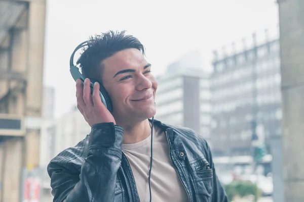 Jovem bonito homem com fones de ouvido posando nas ruas da cidade — Fotografia de Stock