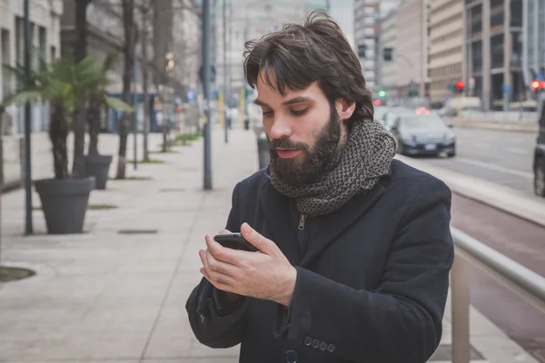 Młody przystojny brodaty człowiek SMS-y na ulicach miasta — Zdjęcie stockowe