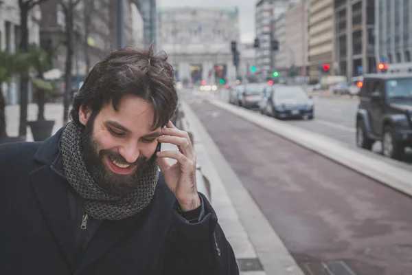 Fiatal jóképű szakállas ember beszél telefonon — Stock Fotó