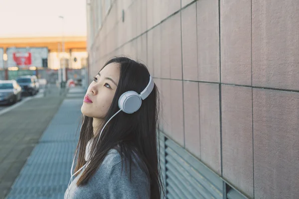 Menina chinesa bonita nova com fones de ouvido — Fotografia de Stock