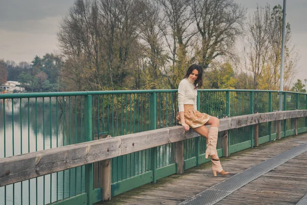 Beautiful young woman posing on a bridge — Stock Photo, Image