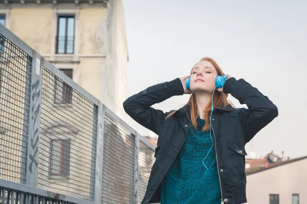 Gyönyörű lány pózol a város utcáin fejhallgató — Stock Fotó