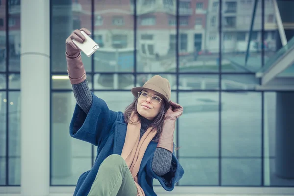 Vacker ung brunett med en selfie på stadens gator — Stockfoto