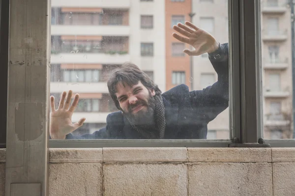 Young handsome bearded man posing behind a glass — Stock Photo, Image