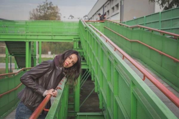 Beautiful young brunette posing on a bridge — Stock Photo, Image