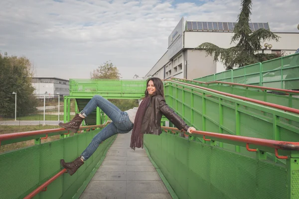 Beautiful young brunette posing on a bridge — Stock Photo, Image