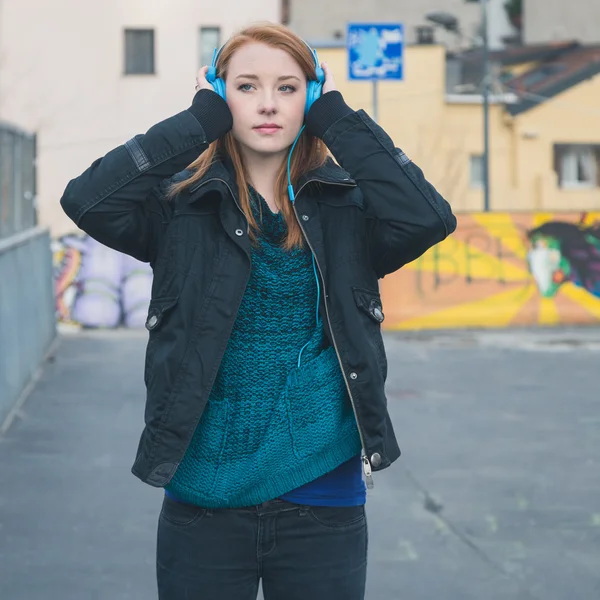 Beautiful girl with headphones posing in the city streets — Stock Photo, Image