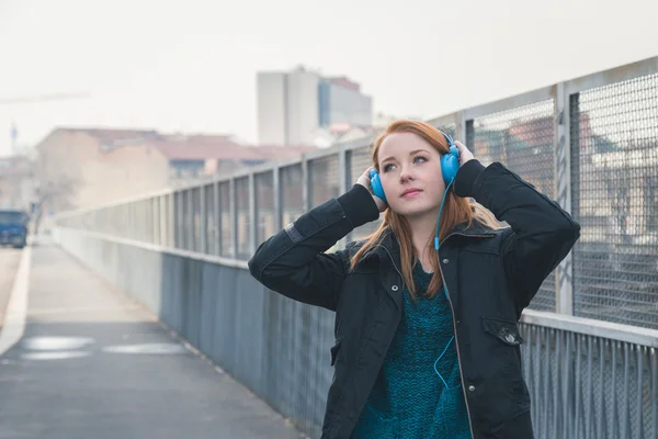 Beautiful girl with headphones posing in the city streets — Stock Photo, Image