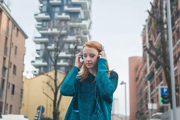 Vacker flicka lyssna på musik på stadens gator — Stockfoto