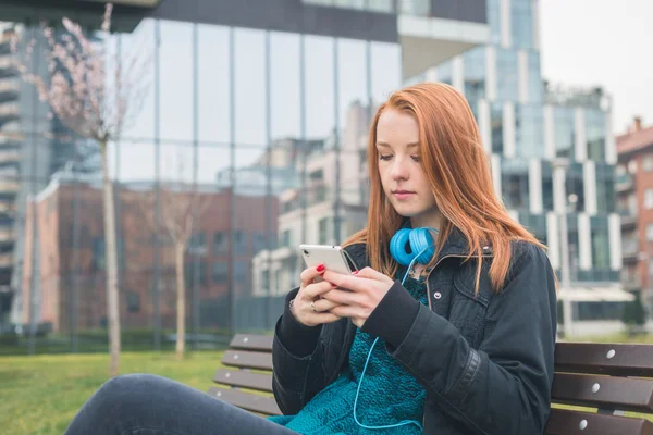 Beautiful girl texting on a bench — Stock Photo, Image